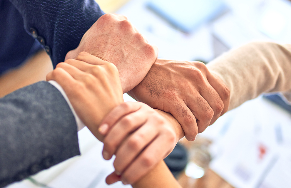 people holding hands symbolizing the importance of community spirit at work